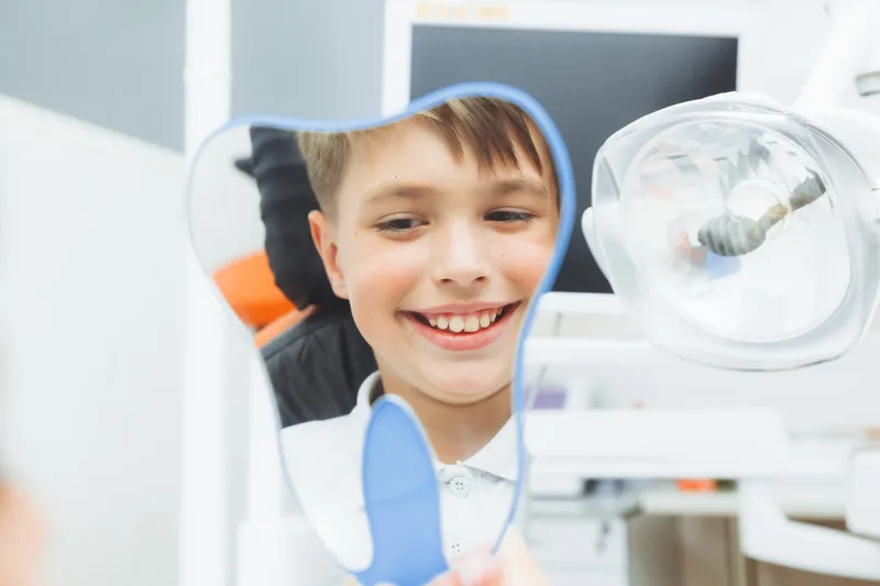 A child smiling in the mirror after a pediatric dental visit